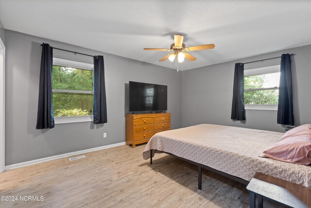 bedroom featuring light wood-type flooring, ceiling fan, and multiple windows