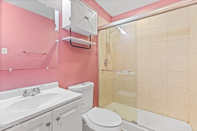 bathroom with a shower with door, vanity, and toilet