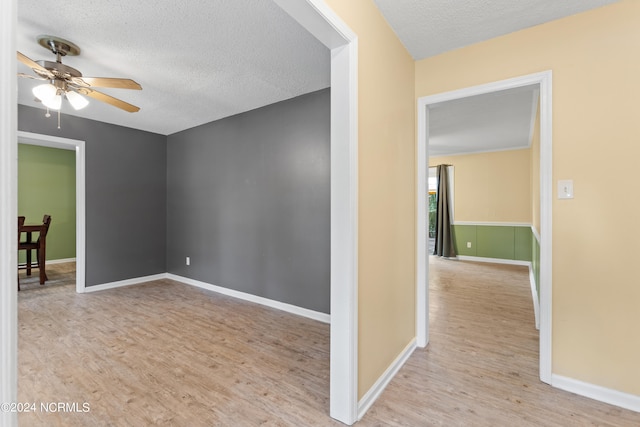 empty room featuring a textured ceiling, ceiling fan, and light hardwood / wood-style flooring