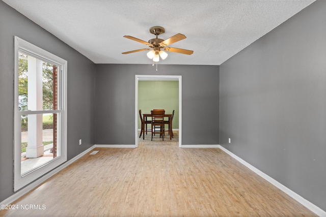 spare room featuring a textured ceiling, ceiling fan, and light hardwood / wood-style flooring