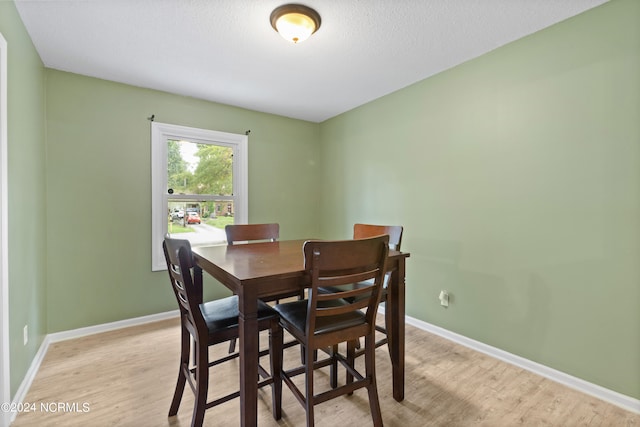 dining space featuring light wood-type flooring and a textured ceiling