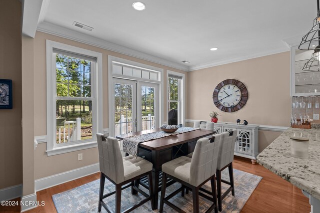 dining space featuring hardwood / wood-style flooring, plenty of natural light, and crown molding