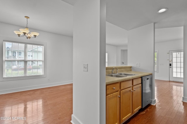 kitchen with wood-type flooring, stainless steel dishwasher, sink, and a healthy amount of sunlight