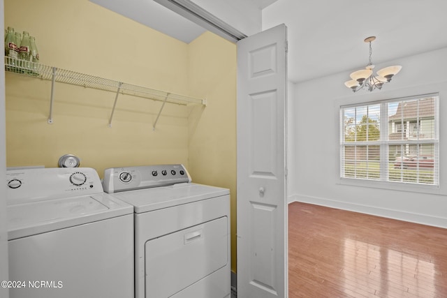 laundry room featuring wood-type flooring, a chandelier, and washing machine and dryer