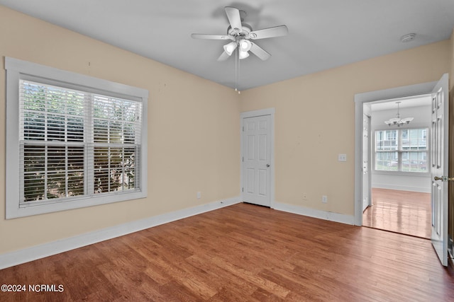 unfurnished room featuring ceiling fan with notable chandelier and hardwood / wood-style floors