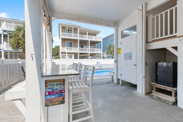 view of patio with a fenced in pool and a balcony