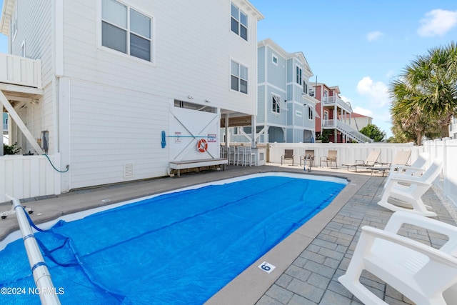 pool featuring fence, a patio area, and a residential view