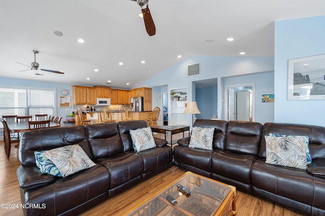 living room featuring ceiling fan, vaulted ceiling, visible vents, and light wood-type flooring