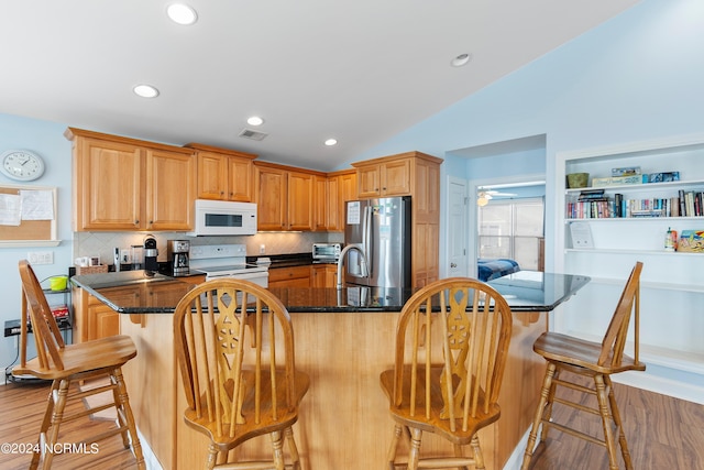 kitchen with tasteful backsplash, white appliances, a kitchen breakfast bar, lofted ceiling, and hardwood / wood-style flooring