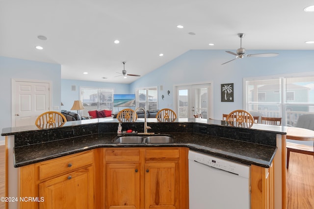 kitchen with dark stone counters, vaulted ceiling, sink, dishwasher, and french doors