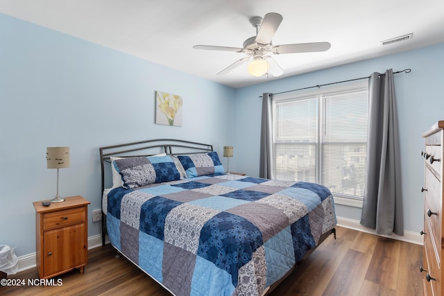 bedroom featuring visible vents, baseboards, wood finished floors, and ceiling fan