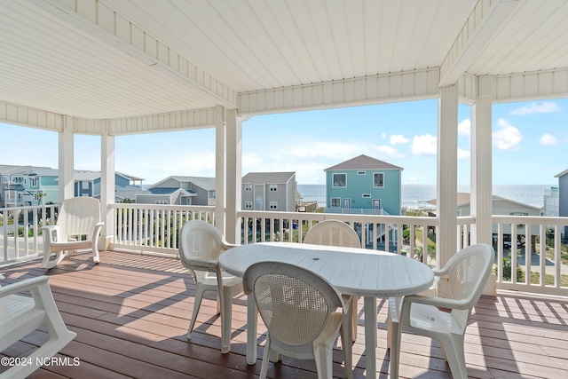 wooden deck featuring outdoor dining area, a water view, and a residential view