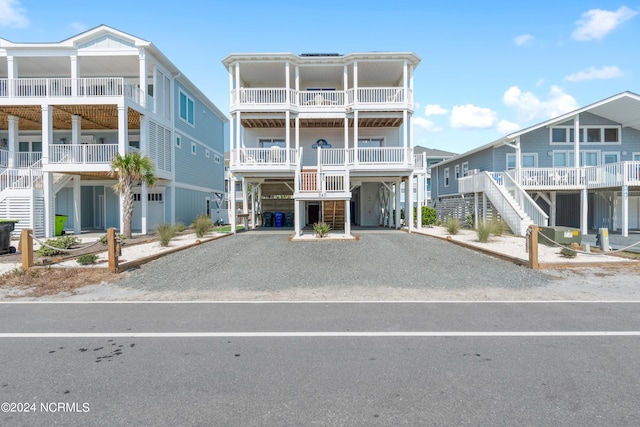 view of building exterior featuring gravel driveway, stairs, and a carport