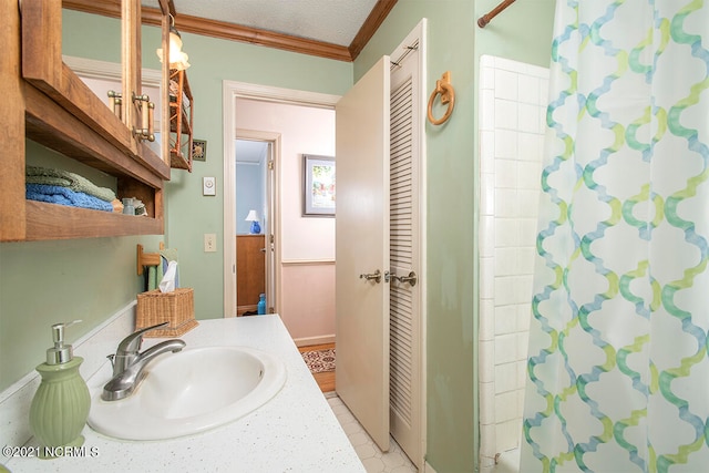 bathroom featuring vanity, a textured ceiling, walk in shower, ornamental molding, and tile patterned floors