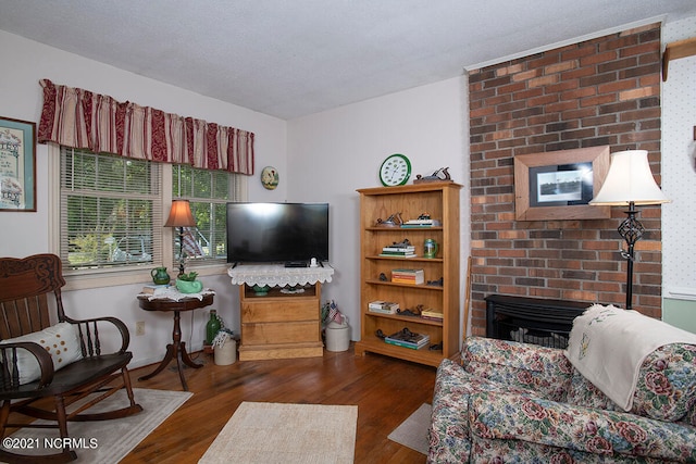 living room featuring a textured ceiling, a fireplace, and dark wood-type flooring