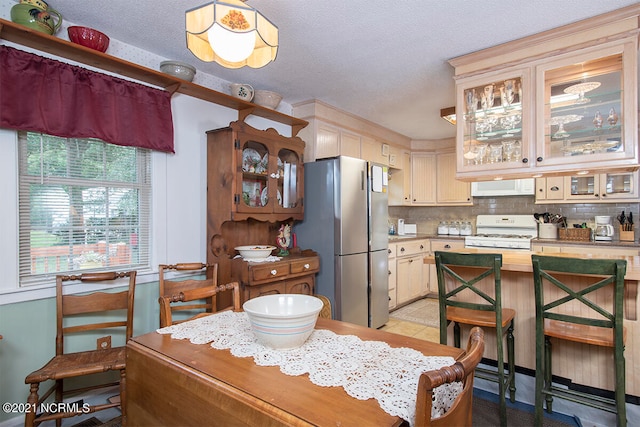 kitchen featuring stainless steel fridge, tasteful backsplash, a textured ceiling, white gas range, and ventilation hood