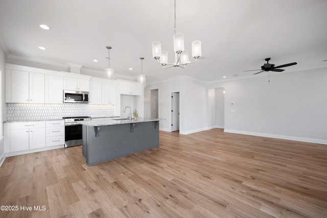 kitchen featuring stainless steel appliances, white cabinetry, sink, and decorative light fixtures