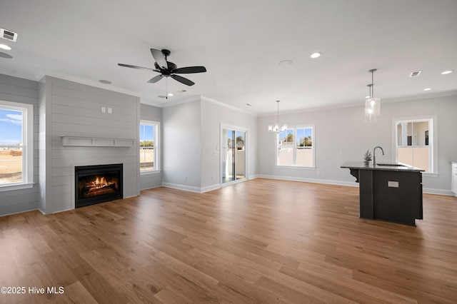 unfurnished living room featuring sink, light hardwood / wood-style flooring, ornamental molding, and a large fireplace