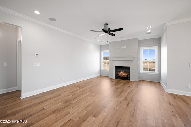 unfurnished living room featuring crown molding, light hardwood / wood-style flooring, a large fireplace, and ceiling fan