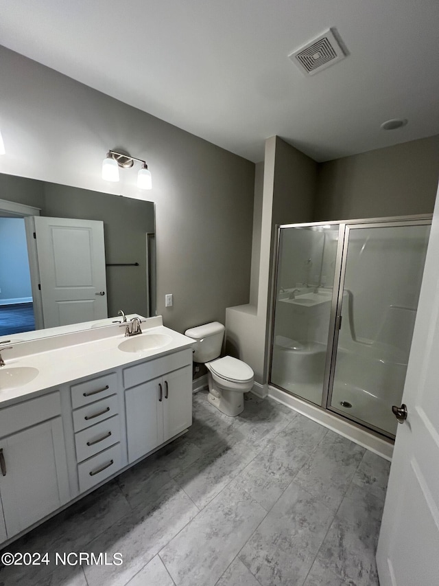 bathroom with vanity, toilet, and a shower with door