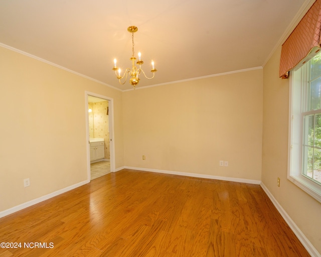 empty room featuring an inviting chandelier, wood-type flooring, and ornamental molding