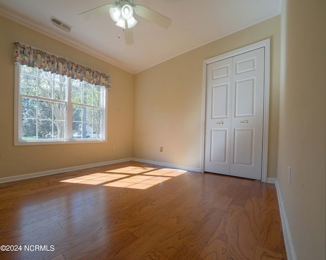 unfurnished bedroom featuring light hardwood / wood-style floors, ornamental molding, ceiling fan, and a closet