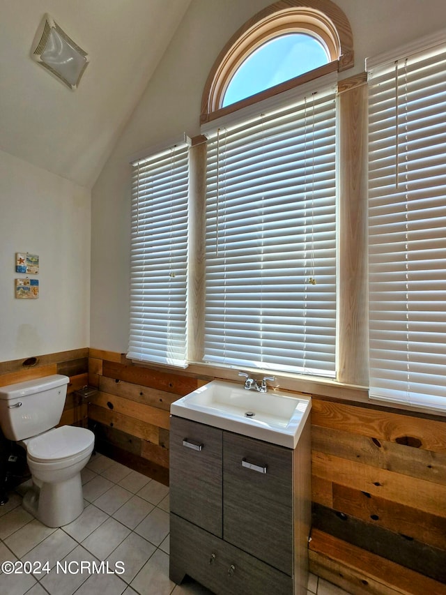 bathroom featuring tile patterned flooring, vaulted ceiling, vanity, and toilet