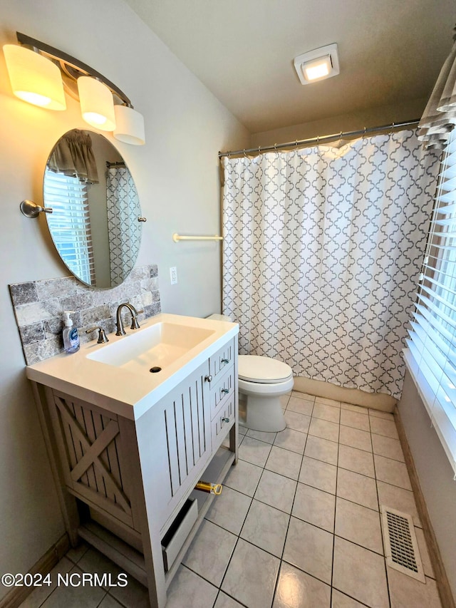 bathroom featuring vanity, tile patterned flooring, toilet, and a wealth of natural light