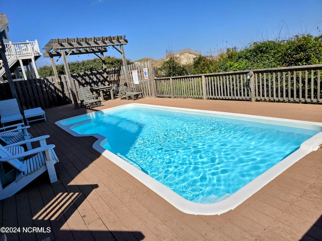 view of swimming pool with a wooden deck and a pergola