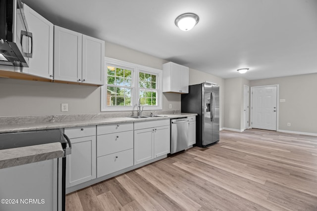 kitchen with light hardwood / wood-style flooring, appliances with stainless steel finishes, sink, and white cabinets