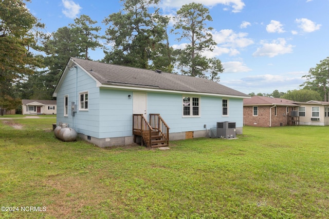 rear view of property featuring a yard and central AC unit