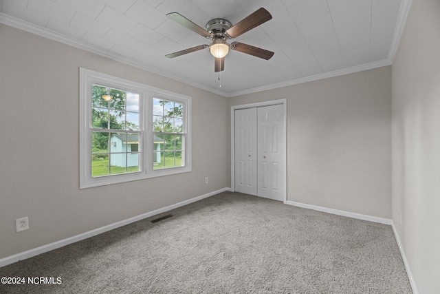 unfurnished bedroom with a closet, ornamental molding, carpet, and ceiling fan