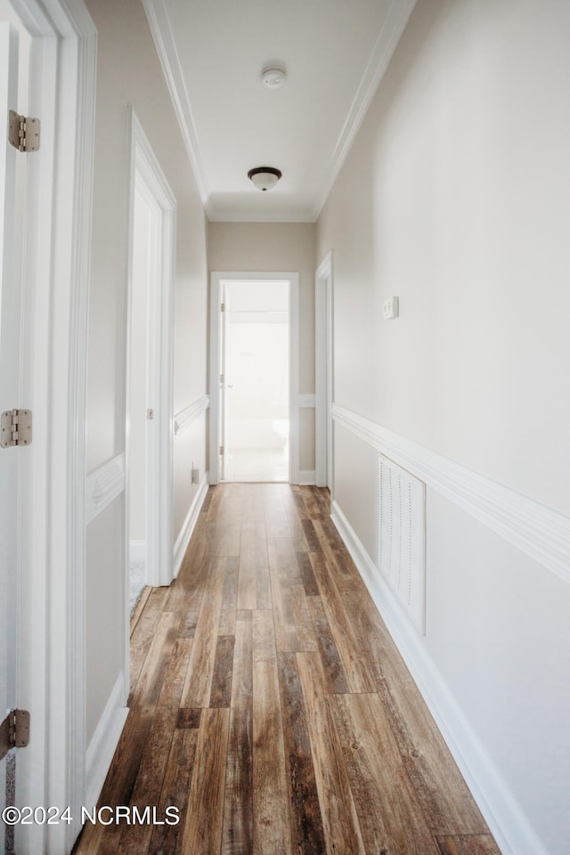 corridor with ornamental molding and hardwood / wood-style floors