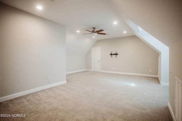 additional living space with ceiling fan, carpet floors, and lofted ceiling with skylight