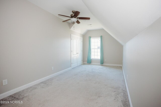 additional living space with ceiling fan, light colored carpet, and lofted ceiling