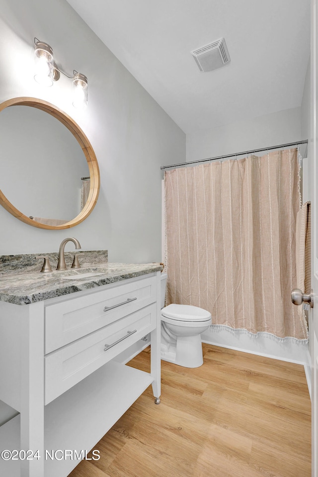 full bathroom with vanity, hardwood / wood-style floors, shower / bath combo, and toilet