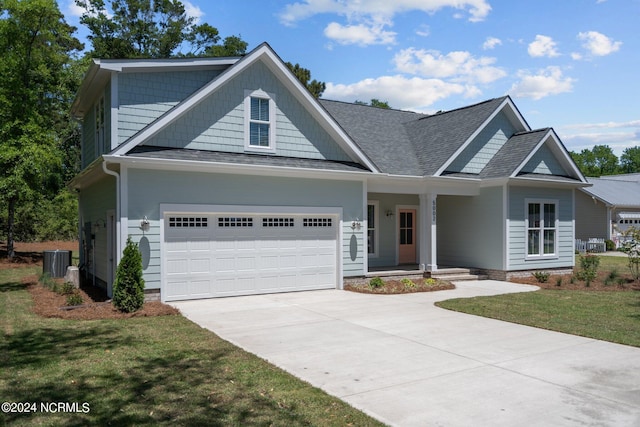 craftsman-style home with central AC unit, a garage, and a front yard