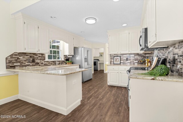 kitchen with light stone countertops, stainless steel appliances, dark hardwood / wood-style floors, kitchen peninsula, and white cabinetry