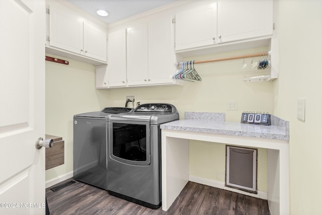 washroom featuring dark wood-type flooring, washing machine and clothes dryer, and cabinets