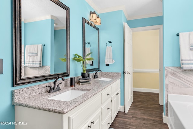 bathroom featuring wood-type flooring, ornamental molding, a tub to relax in, and vanity