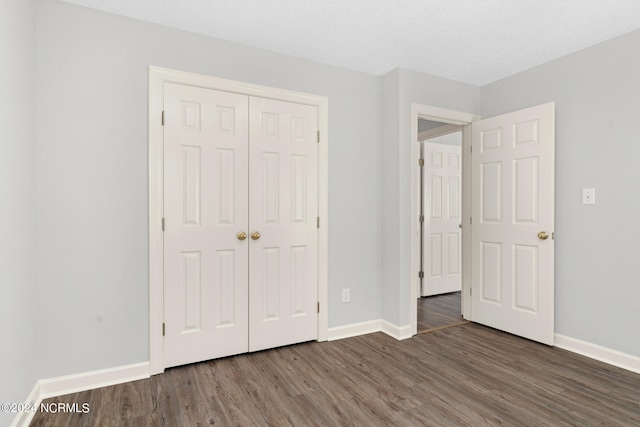 unfurnished bedroom with a closet, dark hardwood / wood-style floors, and a textured ceiling