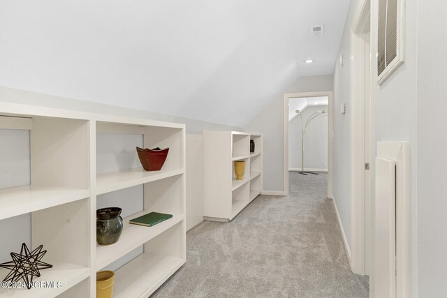 corridor with lofted ceiling and light carpet