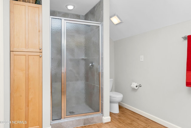 bathroom featuring walk in shower, hardwood / wood-style flooring, and toilet