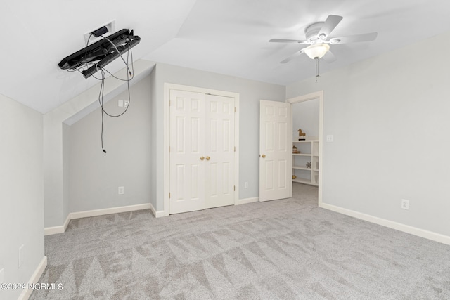 unfurnished bedroom featuring lofted ceiling, a closet, light colored carpet, and ceiling fan