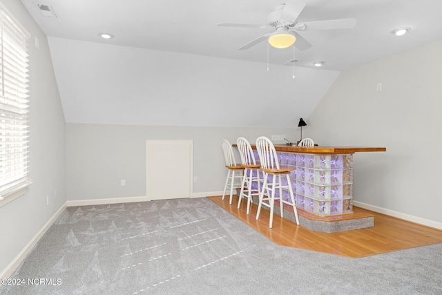 bar with ceiling fan, hardwood / wood-style flooring, and lofted ceiling