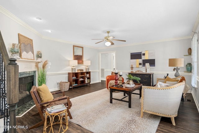 living room featuring dark wood-type flooring, ceiling fan, crown molding, and a tiled fireplace