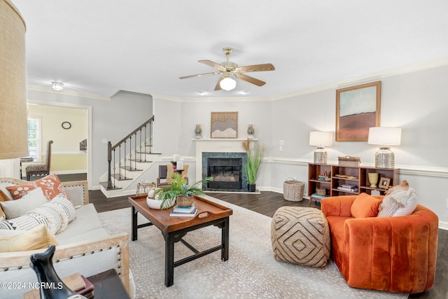 living room featuring ceiling fan, ornamental molding, hardwood / wood-style flooring, and a tile fireplace