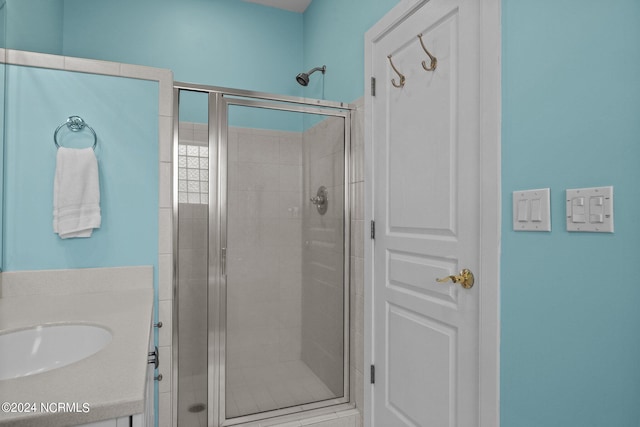 bathroom with a shower with shower door and sink