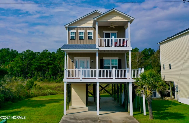 raised beach house with a front lawn, a carport, and ceiling fan