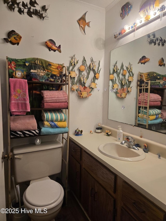 bathroom featuring toilet, vanity, and crown molding